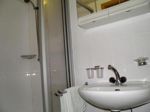 a white bathroom with a sink and a shower at Pension Brunnen in Dresden