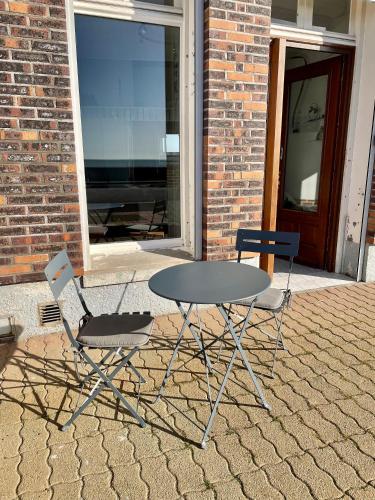 une table et deux chaises assises à côté d'un bâtiment dans l'établissement Le Front de mer - studio lumineux esplanade Mers, à Mers-les-Bains