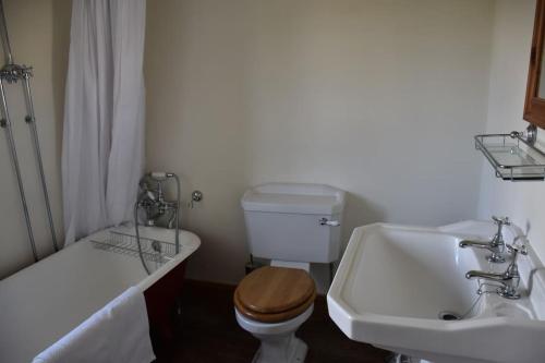 a bathroom with a sink and a toilet and a tub at Riverside Cottage in Lower Slaughter