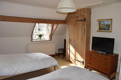 a bedroom with two beds and a flat screen tv at Riverside Cottage in Lower Slaughter