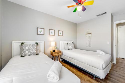 two beds in a room with white walls and wood floors at Warm Welcomes on Wahalla Lane in Glendale