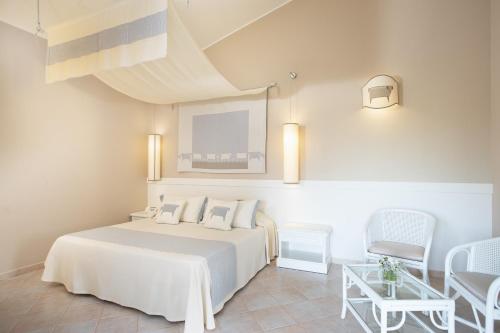 a bedroom with a white bed and a table and chairs at Hotel Baia Di Nora in Pula