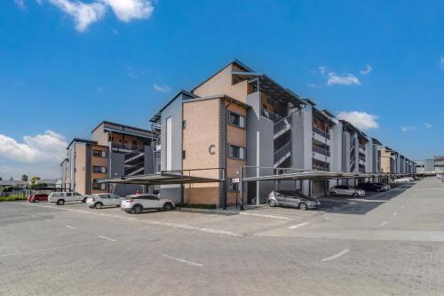 a parking lot with cars parked in front of a building at The Lillies Luxury Apartment in Midrand