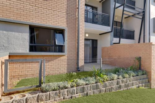 a brick house with a retaining wall and a fence at The Lillies Luxury Apartment in Midrand