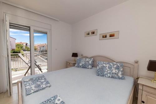 um quarto branco com uma cama e uma varanda em Apartmani Dea em Crikvenica