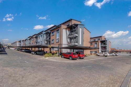 a parking lot with cars parked in front of a building at The Lillies Luxury Apartment in Midrand