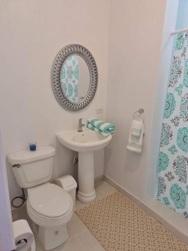 a bathroom with a toilet and a sink and a mirror at Sandpiper Beach Apartments in Palm-Eagle Beach