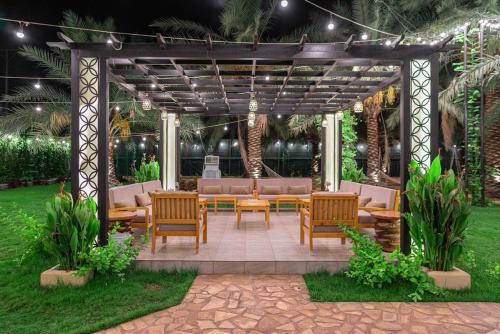 a pergola with chairs and tables in a yard at Ezdan Chalet in Unayzah