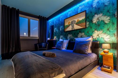 1 dormitorio con 1 cama grande y pared azul en Sunset Appart-Hotel 3 chambres, 2 Salles de Bain, proche Paris, Massy & Orly en Longjumeau