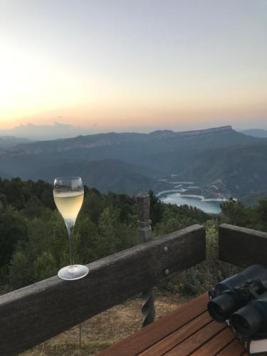 a glass of wine sitting on a railing with a view at Casa de muntanya Can Coll de Susqueda Girona in Susqueda