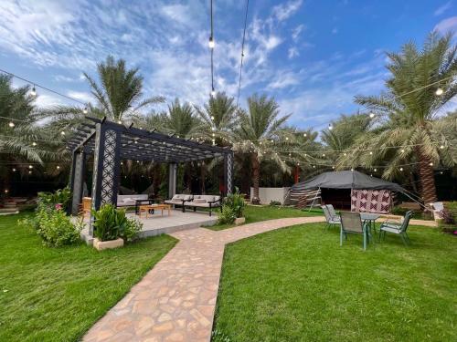 a garden with a gazebo and tables and chairs at Ezdan Chalet in Unayzah