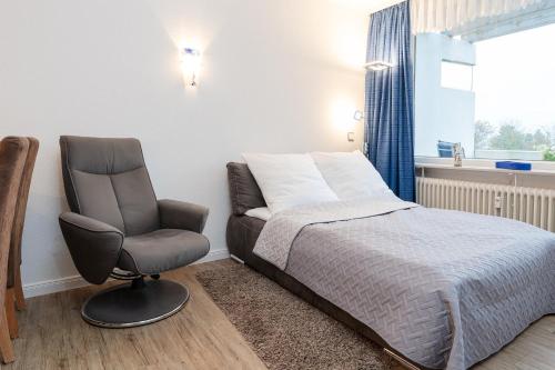 een slaapkamer met een bed en een stoel bij Driftberg 1 Haus A Wohnung 33 in Grömitz