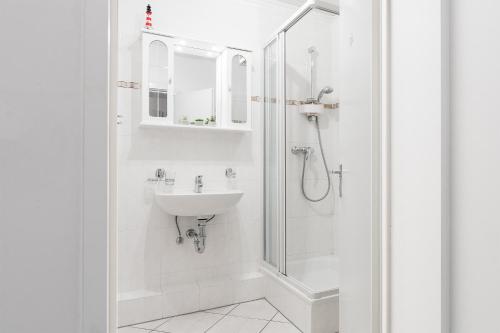een witte badkamer met een wastafel en een douche bij Driftberg 1 Haus A Wohnung 33 in Grömitz