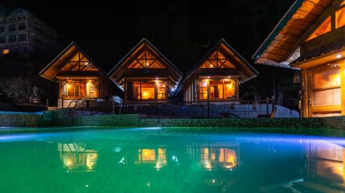 a house with a pool in front of it at night at Wolfandwoods in Khajjiar 