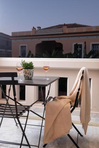 a table with two glasses of wine on a balcony at Epoch House & The Orange Shop - Adults Only in Nafplio