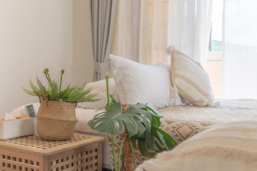 a bedroom with a bed with pillows and a table with plants at HiHi Skylight in Hengchun