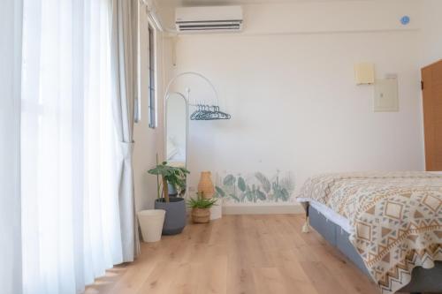 a bedroom with a bed with white walls and wooden floors at HiHi Skylight in Hengchun