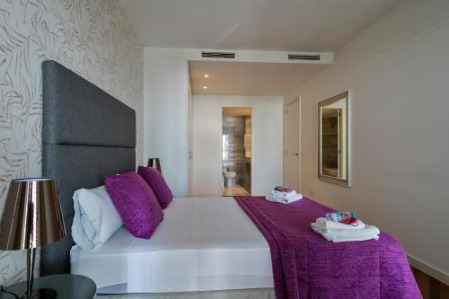 a bedroom with a large white bed with purple sheets at Alcam Llum Deluxe in Barcelona