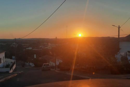 a sunset over a city with the sun setting on a hill at Sunrise Monsaraz - Telheiro e Jardim - 4 pessoas in Monsaraz