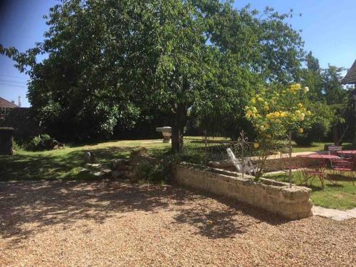 un jardín con un árbol y una pared de piedra en Maison avec exterieur, en Bû