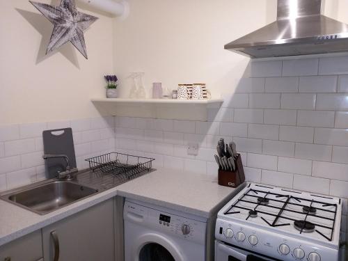 a white kitchen with a stove and a sink at Belv House in Weymouth