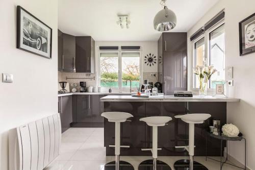 une cuisine avec des placards noirs et un comptoir avec des tabourets dans l'établissement Independent house with garden - Airport CDG and Exposition center of Villepinte, à Sevran