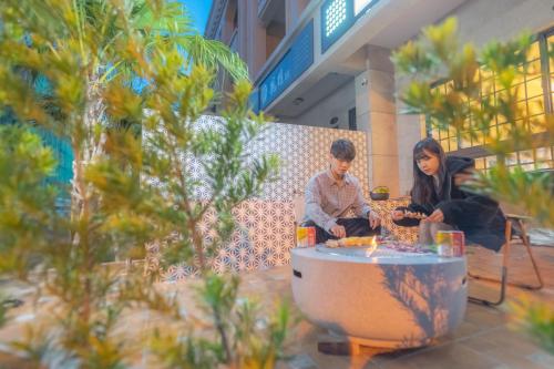 a man and woman sitting around a table in a building at HiHi Skylight in Hengchun