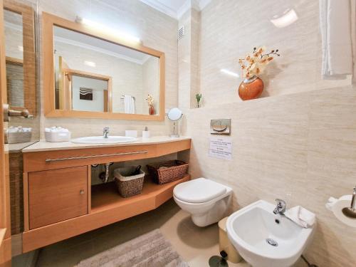 a bathroom with a sink and a toilet and a mirror at Apartment Rocha Oceano Azul Charming in Portimão