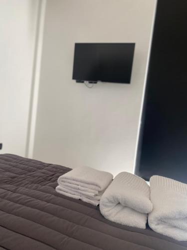 1 cama con 3 toallas y TV en la pared en 126 Suite Centro II en Suipacha