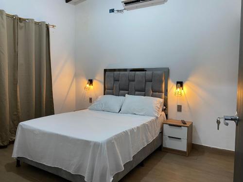 1 dormitorio con 1 cama grande con sábanas blancas y mesita de noche en Malibu beach, en Punta de Piedra