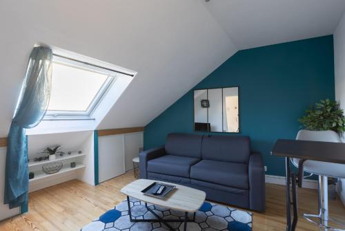 un salon avec un canapé et un mur bleu dans l'établissement L'appart K-ractère- City, cosy et design pour 4 pers, au Mans