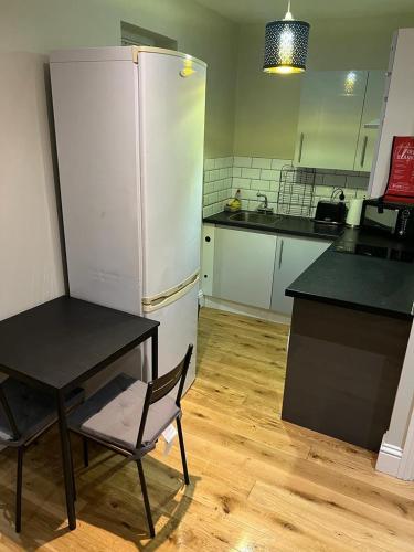 a kitchen with a table and a white refrigerator at Lovely 1 bedroom apartment with on street parking in London