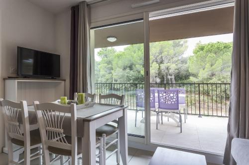 a dining room with a table and chairs and a balcony at Residhotel Résidence Pont du Gard in Remoulins