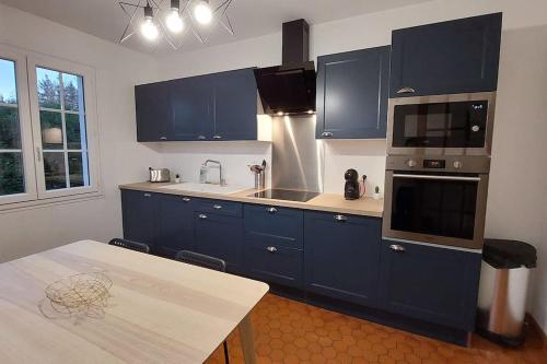 a kitchen with blue cabinets and a table in it at La villa du lac à Mesnil Saint Père in Mesnil-Saint-Père