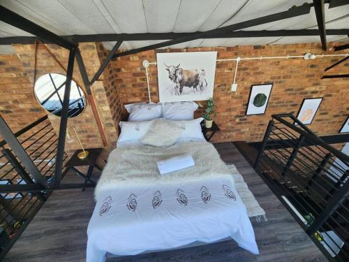 una camera con un grande letto in un muro di mattoni di 353 Maboneng on Craft a Johannesburg