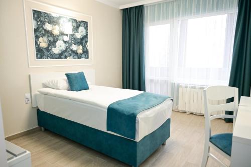 a bedroom with a bed and a table and a window at Роял Шумен in Shumen