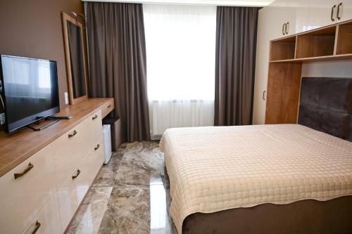 a bedroom with a bed and a flat screen tv at Роял Шумен in Shumen