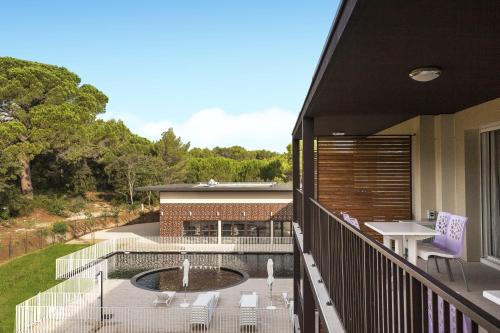 a balcony with a pool and a table and chairs at Residhotel Résidence Pont du Gard in Remoulins