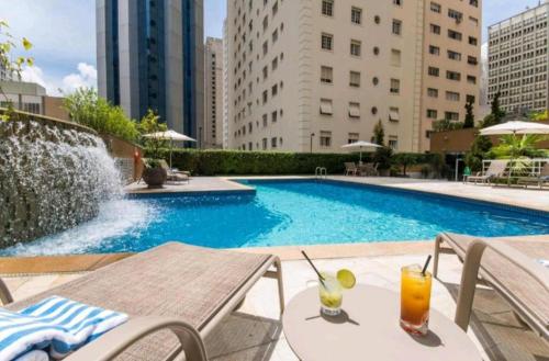 una piscina con una mesa y dos bebidas. en INTERNATiONAL PLAZA PAULISTA JARDINS ROOFTOT THE VIEW, en São Paulo