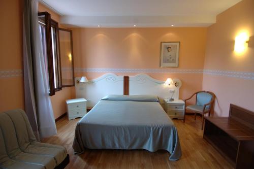 una camera con letto, sedia e divano di Albergo Ristorante Flora a Vittorio Veneto
