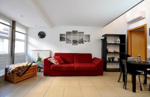 a living room with a red couch and a table at Loft ristrutturato vicino M4 Argonne - San Benigno in Milan