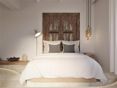 a bedroom with a large white bed with a wooden headboard at F Fine Suites - Adults Only in Líndos