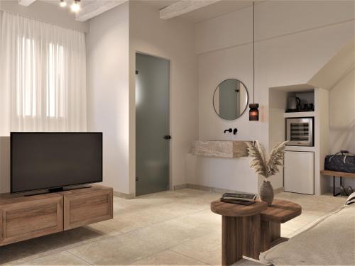 a living room with a flat screen tv on a wooden stand at F Charm all Suites - Adults Only in Lindos