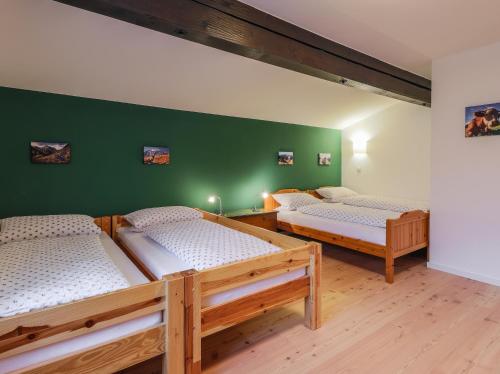 two beds in a room with a green wall at DasBeckHaus - Chiemgau Karte in Inzell