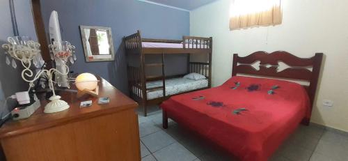 um quarto com uma cama vermelha, uma secretária e beliches em Casinha de hóspedes aconchegante. em São Sebastião