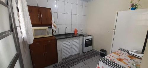 uma pequena cozinha com um micro-ondas e um fogão em Casinha de hóspedes aconchegante. em São Sebastião