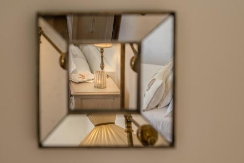 a mirror reflecting a bedroom with a bed and a lamp at CasaVostra - Ambience Suites in Ostra Vetere