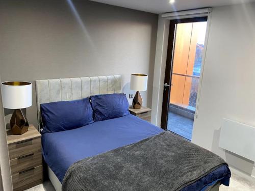 1 dormitorio con cama con sábanas azules y ventana en Luxury 1 bed full apartment with balcony, en Liverpool