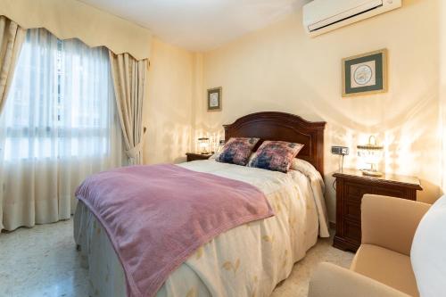 Un dormitorio con una cama grande y una ventana en MalagaSuite Sotomar Apartment, en Torremolinos