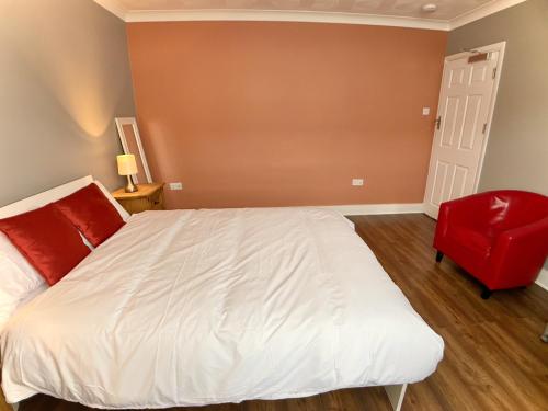 a bedroom with a white bed and a red chair at Richmond HOUSE in Slough
